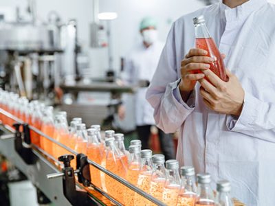 Labor worker working in drink factory production line fruit juice beverage product at conveyor belt.